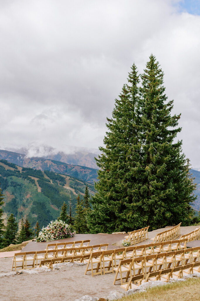 A mountain wedding in Colorado, with a ceremony overlooking the Rocky Mountains, with a large floral installation, planning by destination wedding planner Julian Leaver Events.