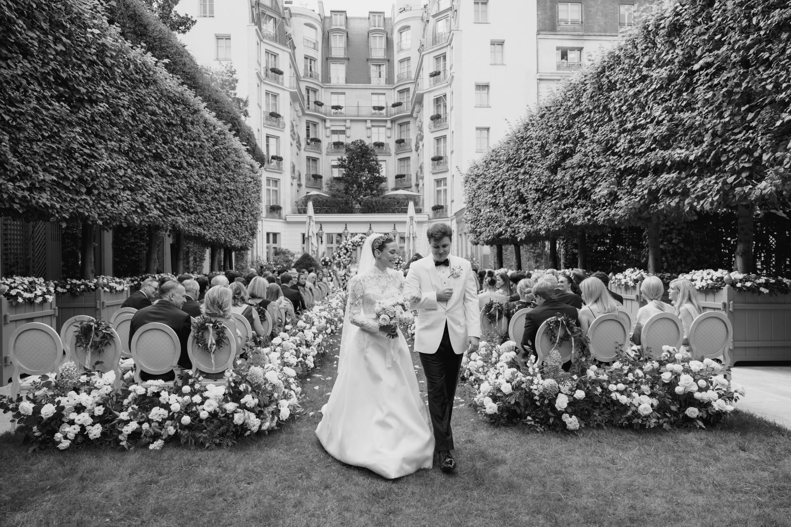Un couple descendant l'allée après leur cérémonie de mariage au Ritz, à Paris, les allées étant recouvertes de fleurs