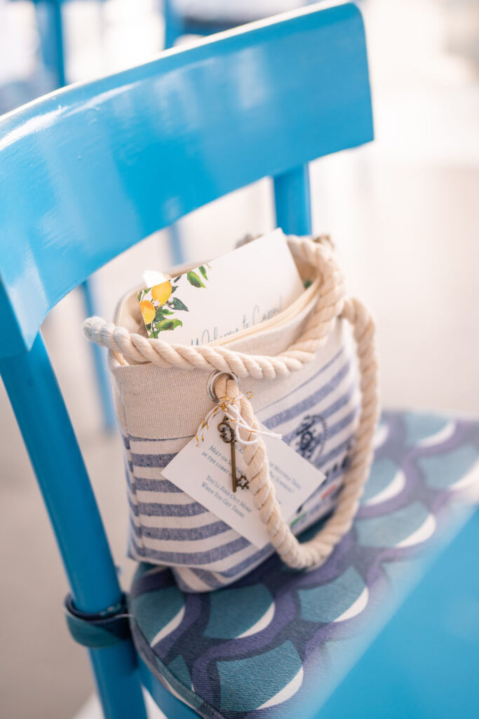 A close-up of a nautical-themed striped canvas bag with rope handles placed on a vibrant blue chair, suggesting a seaside or beach event ambiance.