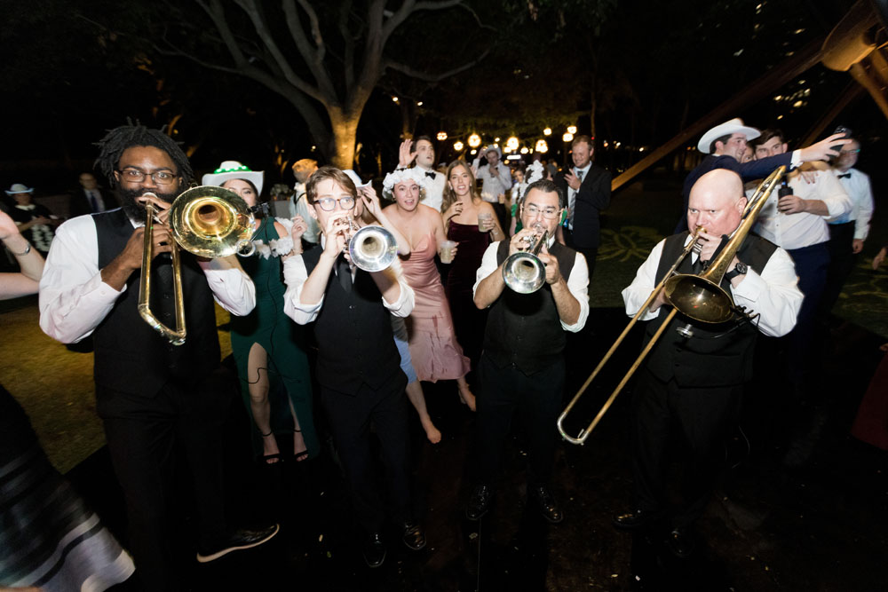 Joyful brass band with trumpets leading the guests in an outdoor night procession, infusing the wedding with lively music.