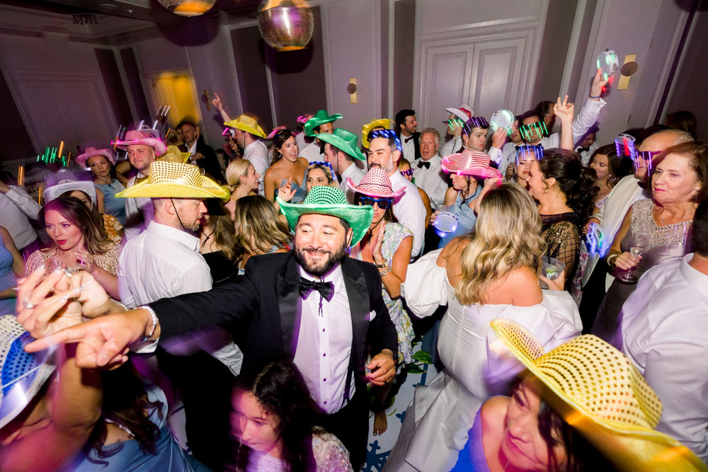 Wedding guests on the dance floor having fun, wearing colorful cowboy hats and partying.