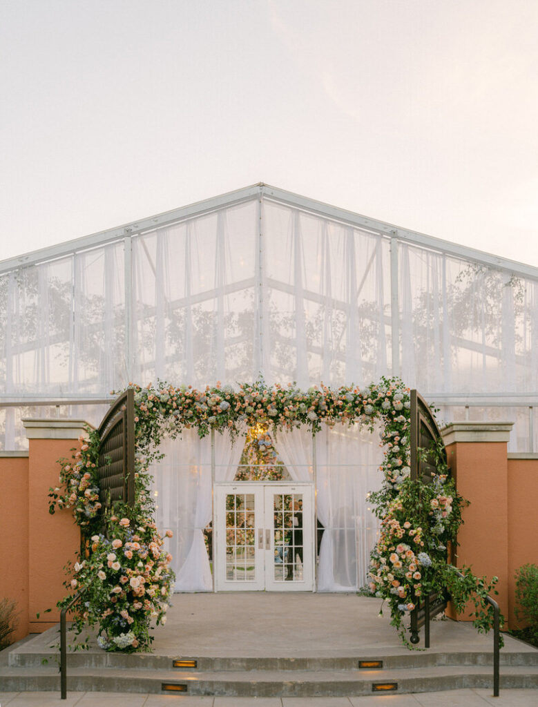 The outside of a large tent, with flowers covering the doors