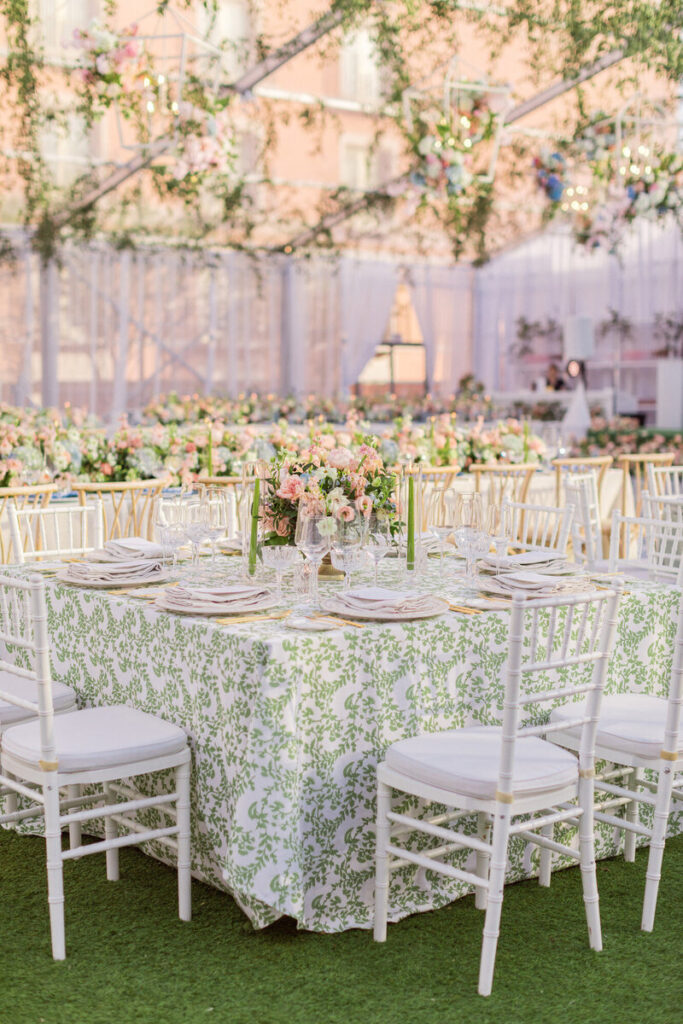 Tented wedding with tables covered in green patterned fabric, with white Chiavari chairs, with flowers hanging from the ceiling - at the Rosewood Mansion