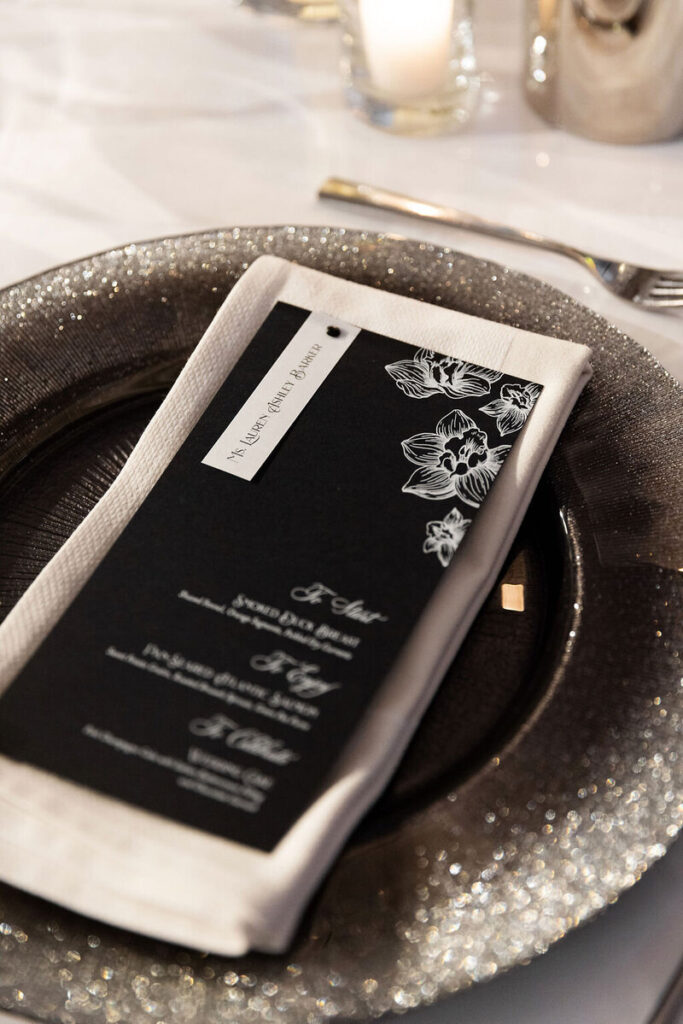 Black menu cards with white writing on a silver charger