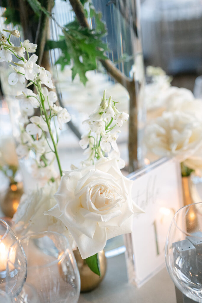 Detail of a white rose flower arrangement, sitting next to an acrylic sign at Current at Pier 59 in NYC