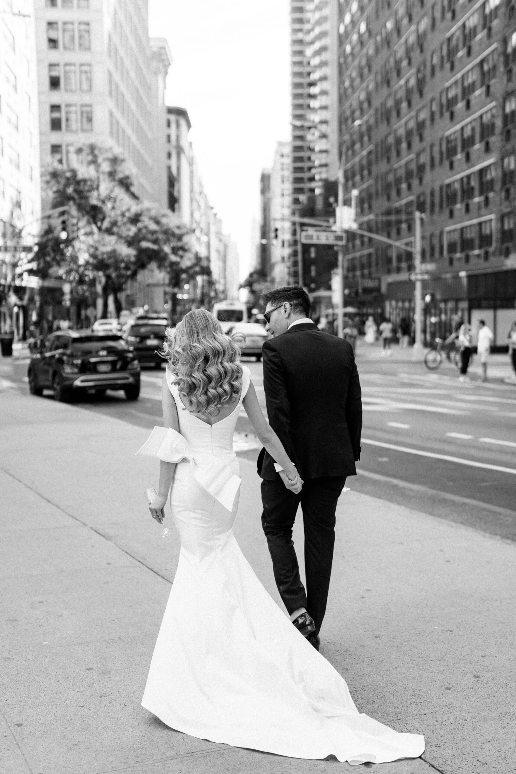 Bride and groom holding hands, walking down the street in NYC