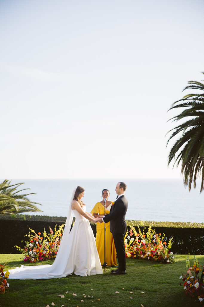 Bride and groom holding hands at their wedding ceremony overlooking the ocean at Bel Air Bay Club in Los Angeles