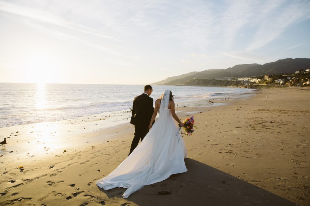 Bride and groom walking on the beach at sunset, outside of their Los Angeles Venue, Bel Air Bay Club