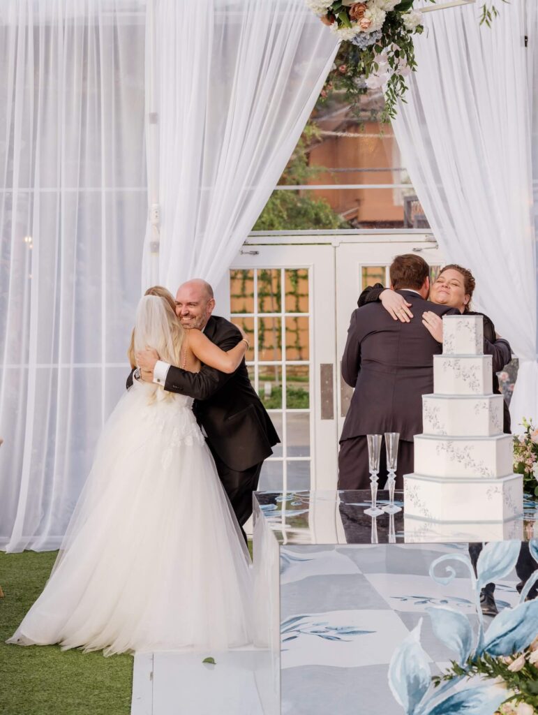 Bride and groom entering a wedding reception, embracing their wedding planners